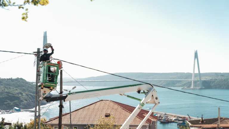 Boğaz kıyısındaki elektrik direğinde sepetli araçla aydınlatma bakımı yapan çalışan