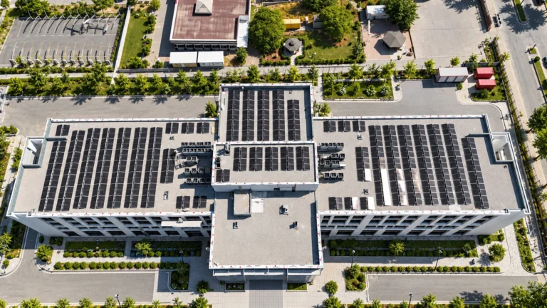 Bir binanın düz çatısındaki güneş panellerinin üstten görünümü; montaj sistemi haberi için temsili görsel.