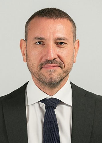Hakan Özmen’in koyu renk takım elbise ve kravatla çekilmiş portresi.