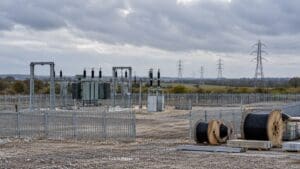 Elektrik bağlantısı bekleyen bir sanayi sahasını, kablo makaralarını ve uzaktaki iletim hatlarını gösteren temsili görsel.