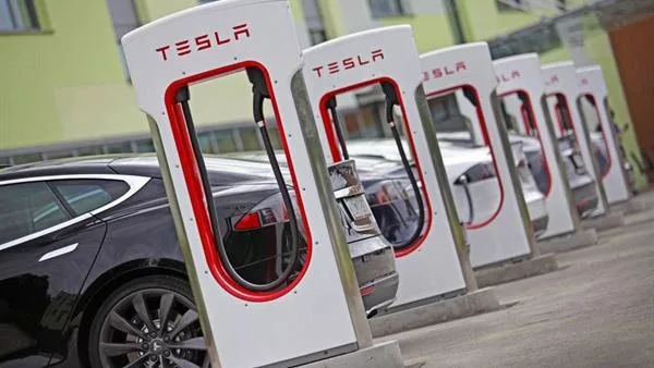Tesla Supercharger üniteleri – arşiv görseli Sıra halinde beyaz ve kırmızı Tesla Supercharger üniteleri ve park edilmiş araçlar; arşiv görseli